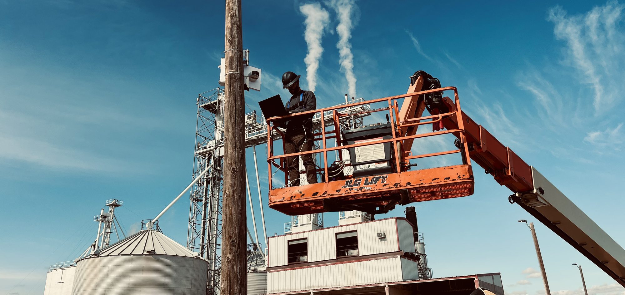 Crossroads Tech Services technician installing equipment from a boom lift at a grain elevator